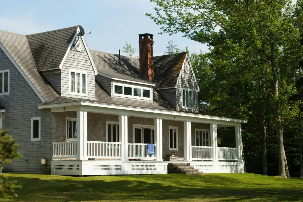 Gray shingled two-story house with a white wraparound porch