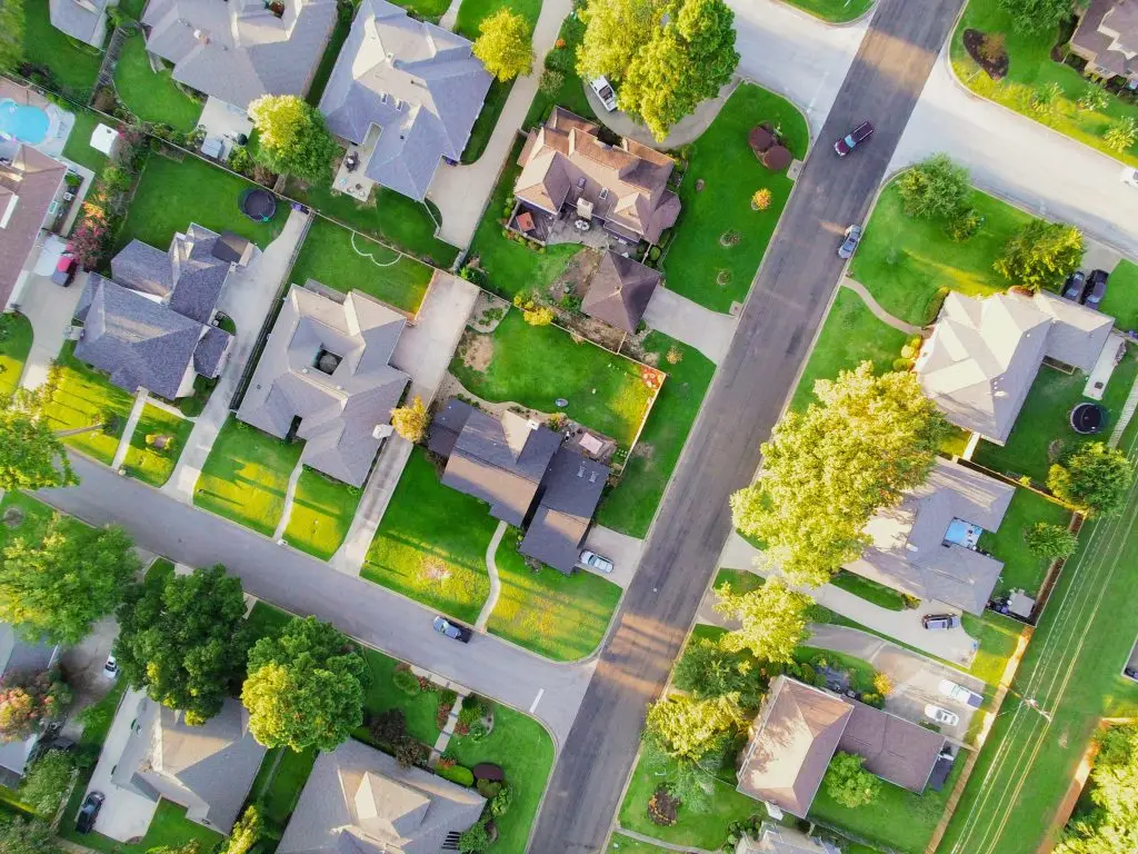 Aerial view of suburban homes with green yards and a quiet street