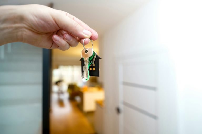 Hand holding a set of house keys at a front door