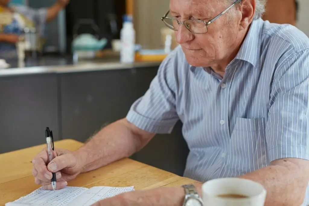 Man sitting at a table writing notes on a sheet of paper