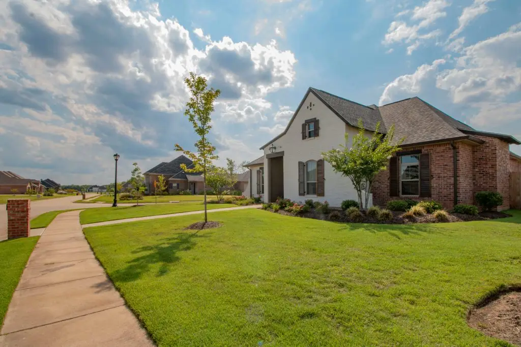 Brick and white stucco home with a curved front walkway and lawn
