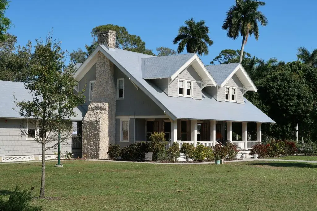Gray craftsman-style home with a stone chimney and covered front porch