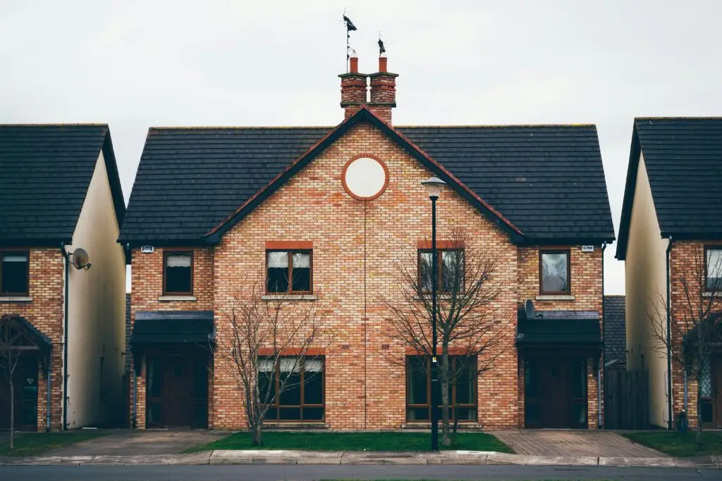 Red brick two-story house with a dark roof and round attic window